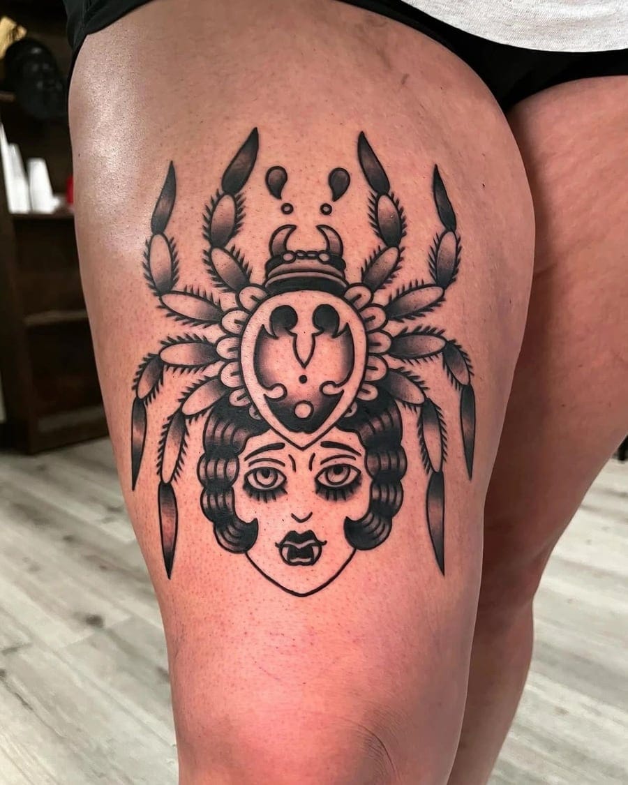 Black and grey thigh tattoo of a woman's face beneath an ornate feathered headdress