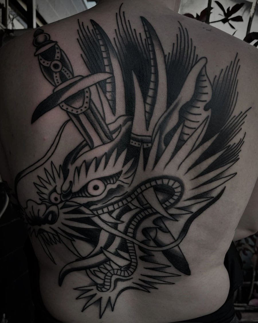 Blackwork tattoo of a dragon wrapped around a dagger across an upper back and shoulder