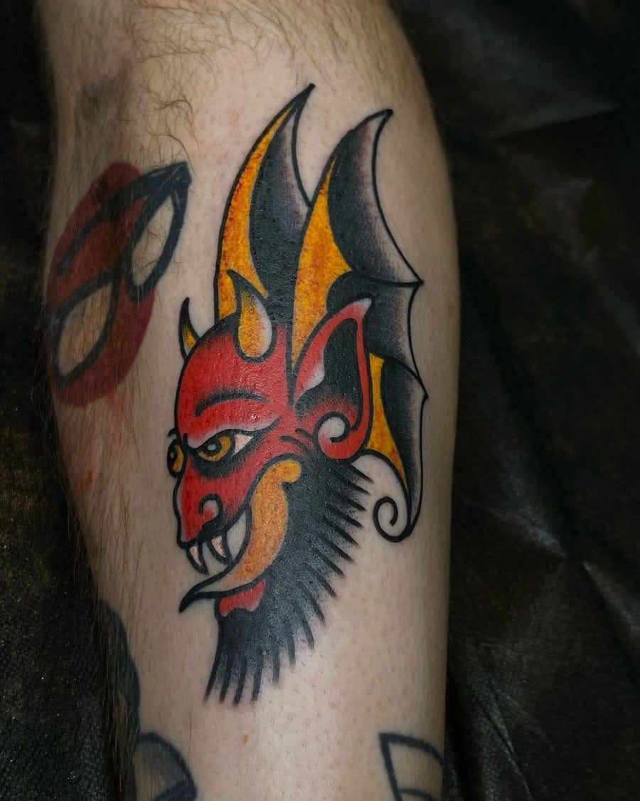 Neo-traditional tattoo of a stylised red devil head on a calf