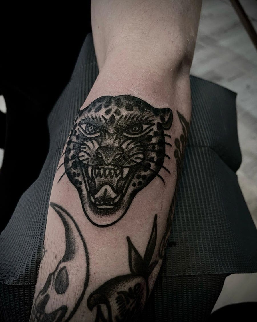 Blackwork tattoo of a snarling leopard head centred over a knee