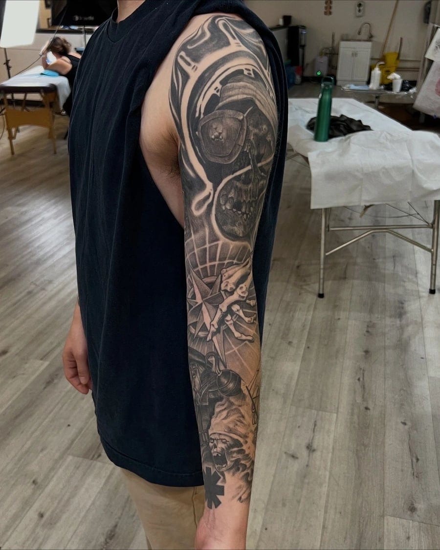 Upper section of a black and grey realism sleeve tattoo, showing shaded detail near the shoulder