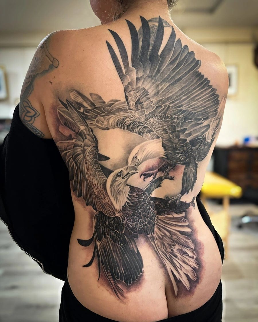 Black and grey realism tattoo of two eagles fighting in flight, covering a full back