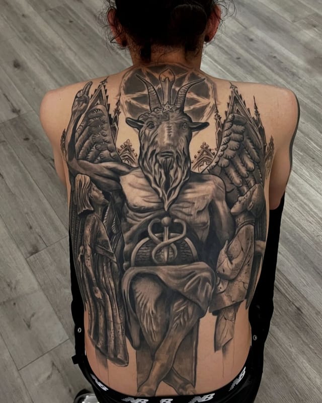 Large black and grey realism back piece with gothic cathedral, winged figure and detailed figures, tattooed at Broken Heart Tattoo in Hillcrest, San Diego